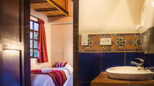 a bathroom with a sink and a bed and a window at Hostal Restaurant La Cigale in Cuenca