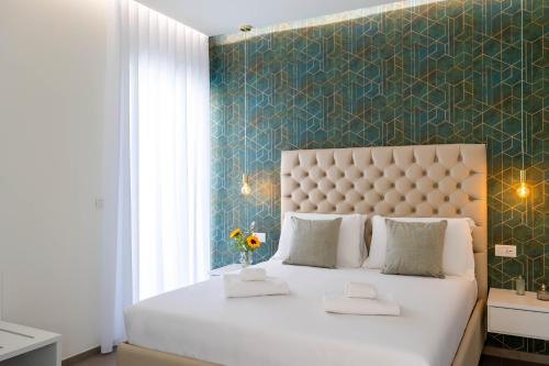 a bedroom with a large white bed with a blue wall at Marea Charme Rooms in Vieste