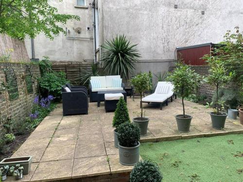 ロンドンにあるStunning London Apartment in Maida Valeの白いベンチと鉢植えの植物が備わるパティオ