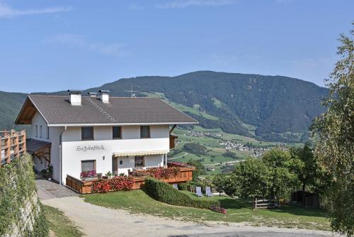 a white house on a hill with mountains in the background at Apartments Schönblick in Mühlbach