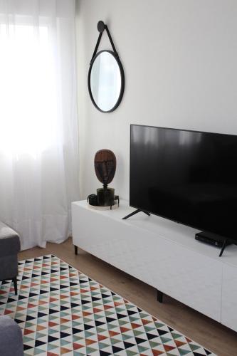 a living room with a flat screen tv on a white cabinet at Cantinho de Benfica in Amadora