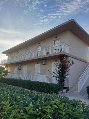 a large white building with a balcony and bushes at Nastazia Studios in Laganas