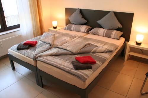 ein großes Bett mit zwei roten Kissen darauf in der Unterkunft Ferienwohnung Dachshübel in Saarbrücken