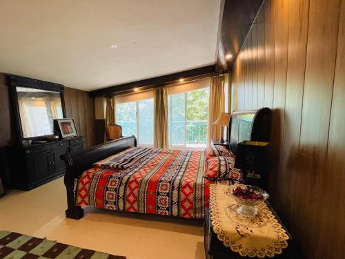 a bedroom with a bed and a window and a table at Misty Mountain in Murree