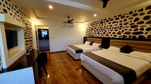 a hotel room with two beds and a television at The Yakshaa Kumartha in Rishīkesh