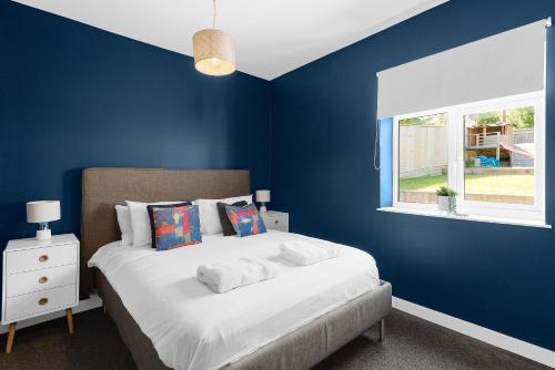 a bedroom with a bed with blue walls and a window at MyCityHaven - The Bathford Annexe in Bath