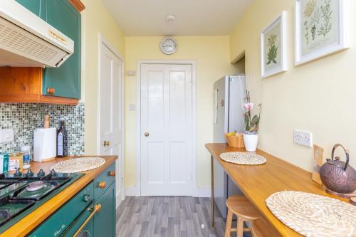 a kitchen with green cabinets and a counter top at Bright & Spacious Double Room with Garden View- Close to Airport & City Centre in Edinburgh