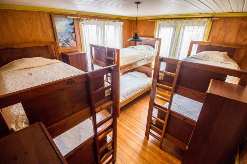 um quarto com 3 beliches e uma janela em 13 Lunas Hostel em Ancud