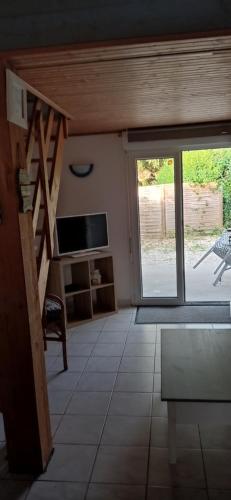 uma sala de estar com uma televisão e uma porta de vidro deslizante em La chatière em Pontaubault