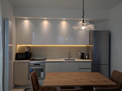 cocina con mesa, fregadero y nevera en Belgrade Waterfront Carmen, en Belgrado