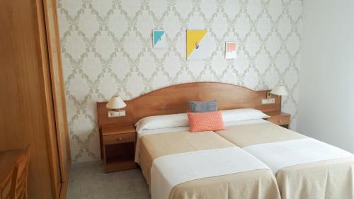 Schlafzimmer mit einem Bett mit orangefarbenem Kissen in der Unterkunft Habitaciones Ninfa in Villalonga