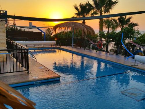 a large swimming pool with a sunset in the background at Astrofegia Beachfront Villa in Pomos