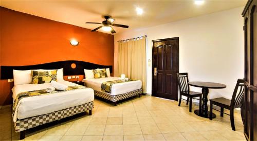 a hotel room with two beds and a table at Hotel Colonial Playa del Carmen in Playa del Carmen