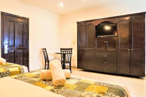 a room with a tv and a table with chairs at Hotel Colonial Playa del Carmen in Playa del Carmen
