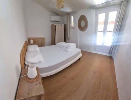 une chambre blanche avec un lit et une fenêtre dans l'établissement maison de village, à Saint-Laurent-de-Carnols