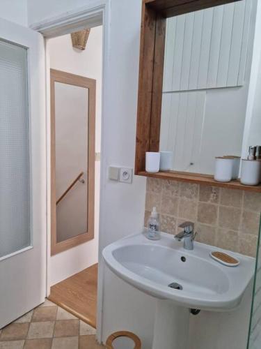 une salle de bain avec un lavabo et un miroir dans l'établissement maison de village, à Saint-Laurent-de-Carnols