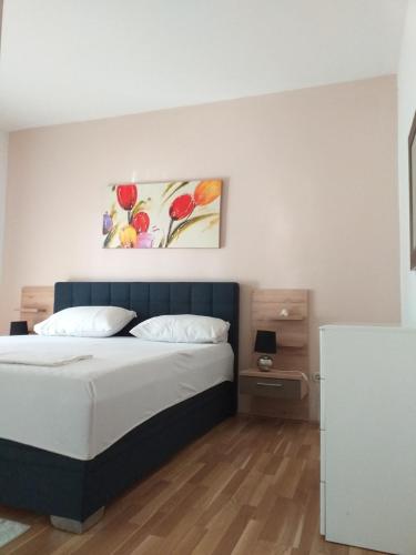 a bedroom with a bed and a painting on the wall at Apartments Golić in Biograd na Moru