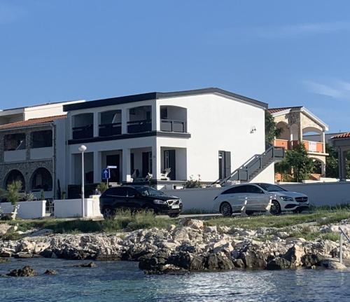 twee auto's geparkeerd voor een wit gebouw bij HausMamaMia in Vir