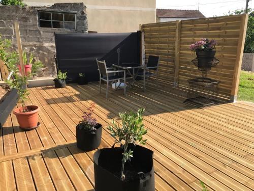 una terraza de madera con mesa y macetas en Le Tipani en Vernon