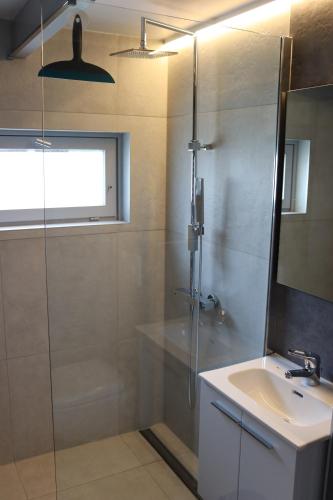 uma casa de banho com um chuveiro e um lavatório. em Bulli Beach House em Koksijde