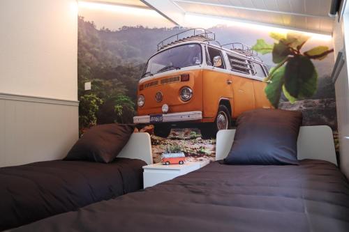 une chambre avec deux lits et une peinture d'une camionnette dans l'établissement Bulli Beach House, à Coxyde