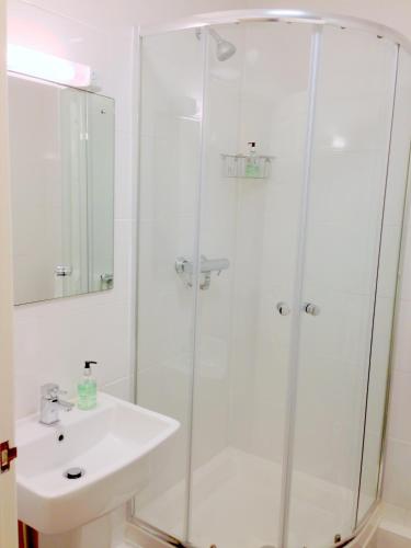 a white bathroom with a shower and a sink at Ely House Hotel in Wolverhampton