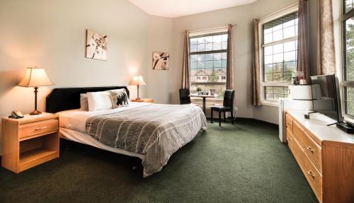 Dormitorio con cama, escritorio y TV en Mountain View Inn, en Canmore