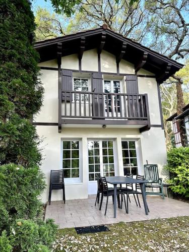 un patio avec une table et des chaises devant une maison dans l'établissement Maison Nature Golf Océan Moliets et Maa Landes, à Moliets-et-Maa