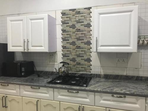a kitchen with white cabinets and a stove in it at Luxury 2 bed apartment. 