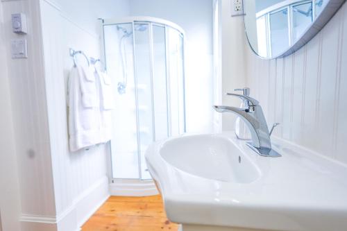 La salle de bains blanche est pourvue d'un lavabo et d'un miroir. dans l'établissement Mahone Bay Bed and Breakfast, à Mahone Bay