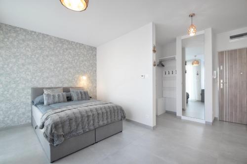 een witte slaapkamer met een bed en een hal bij Apartamenty Ada 2 Resort Klifowa Rewal in Rewal
