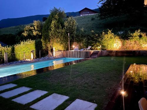 une arrière-cour avec une piscine la nuit dans l'établissement Superbe villa lac d'Annecy avec piscine, à Sévrier