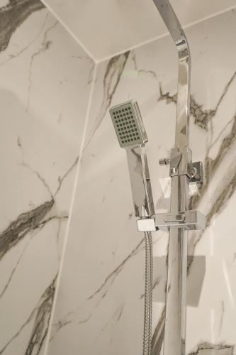 a shower head in a bathroom with marble walls at Novana Aparthotel in Glasgow
