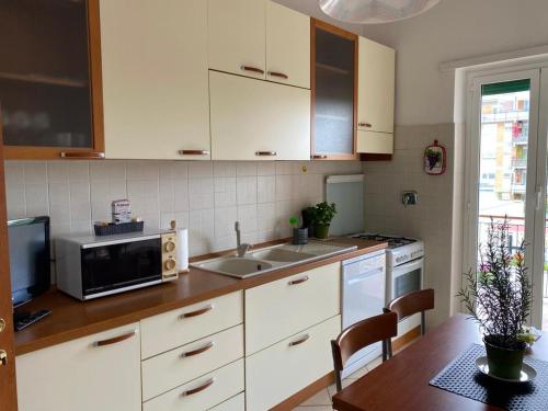 a kitchen with white cabinets and a table with a microwave at Pisana 247 St Peter in Rome