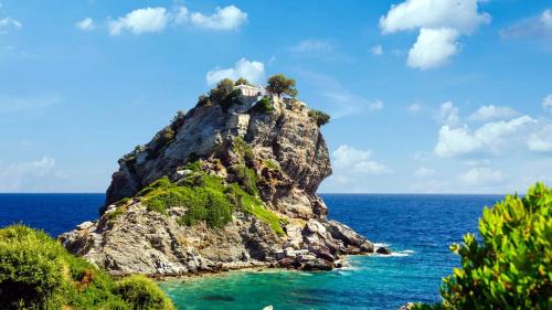 a small island in the ocean with a house on it at RODON Luxury Villas in Skopelos Town