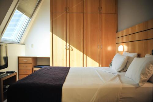 a bedroom with a large white bed and wooden cabinets at San Diego Suítes Lourdes - OFICIAL in Belo Horizonte