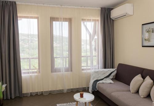 a living room with a couch and two windows at Balchik Garden Palace - 2BD Flat in Balchik