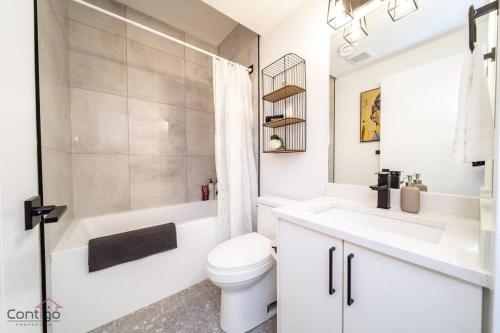Baño blanco con aseo y lavamanos en Luxe New York Style Bsmt Suite, Near DT & WEM, King Bed, WiFi en Edmonton