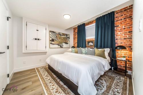 1 dormitorio con cama blanca y pared de ladrillo en Luxe New York Style Bsmt Suite, Near DT & WEM, King Bed, WiFi en Edmonton