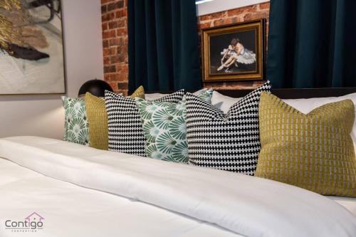 a bunch of pillows on a bed in a room at Luxe New York Style Bsmt Suite, Near DT & WEM, King Bed, WiFi in Edmonton
