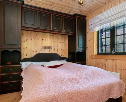ein Schlafzimmer mit einem Bett mit einer rosa Decke in der Unterkunft Leilighet sentralt på Beitostølen in Beitostøl