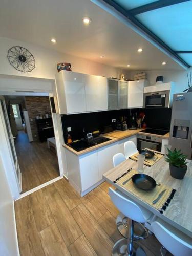 une cuisine avec des armoires blanches et une table et des chaises dans l'établissement Charmante maison avec extérieur à deux pas des remparts, à Aigues-Mortes