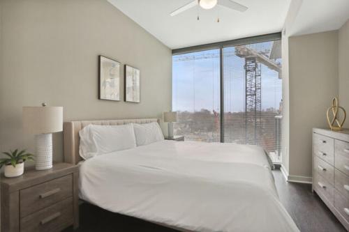 um quarto com uma grande cama branca e uma janela em Piedmont Park 2 bdrm em Atlanta