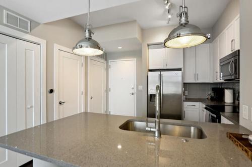 uma cozinha com um lavatório de aço inoxidável e armários brancos em Piedmont Park 2 bdrm em Atlanta
