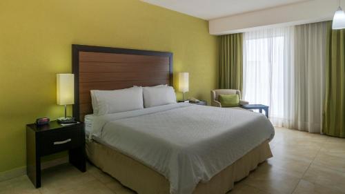 a hotel room with a large bed and a chair at Holiday Inn Express Xalapa by IHG in Xalapa