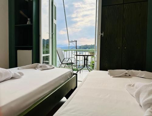 two beds in a room with a view of a balcony at Ancora Hotel in Poros