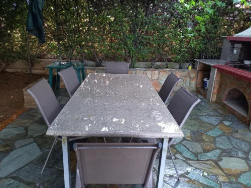 a table and chairs in a yard with a stone patio at TAMMY'S GARDEN HOUSE in Leptokaria