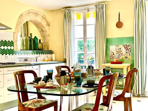 une cuisine avec une table et des chaises en verre dans l'établissement Le Logis Plantagenêt, à Bergerac