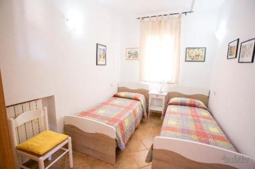 um quarto com 2 camas, uma cadeira e uma janela em Villa Tharros em Capoliveri
