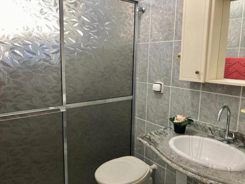 a bathroom with a shower and a toilet and a sink at Apto frente mar na melhor localização de Praia Grande in Praia Grande